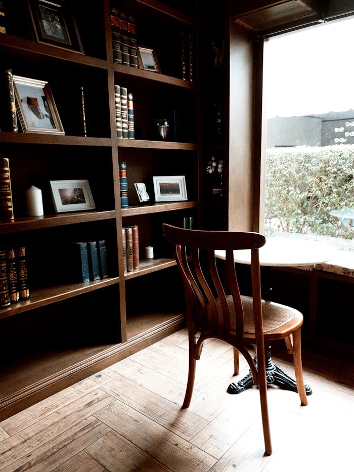 A warm and quiet library corner with bookshelves, wooden chair, and natural light.